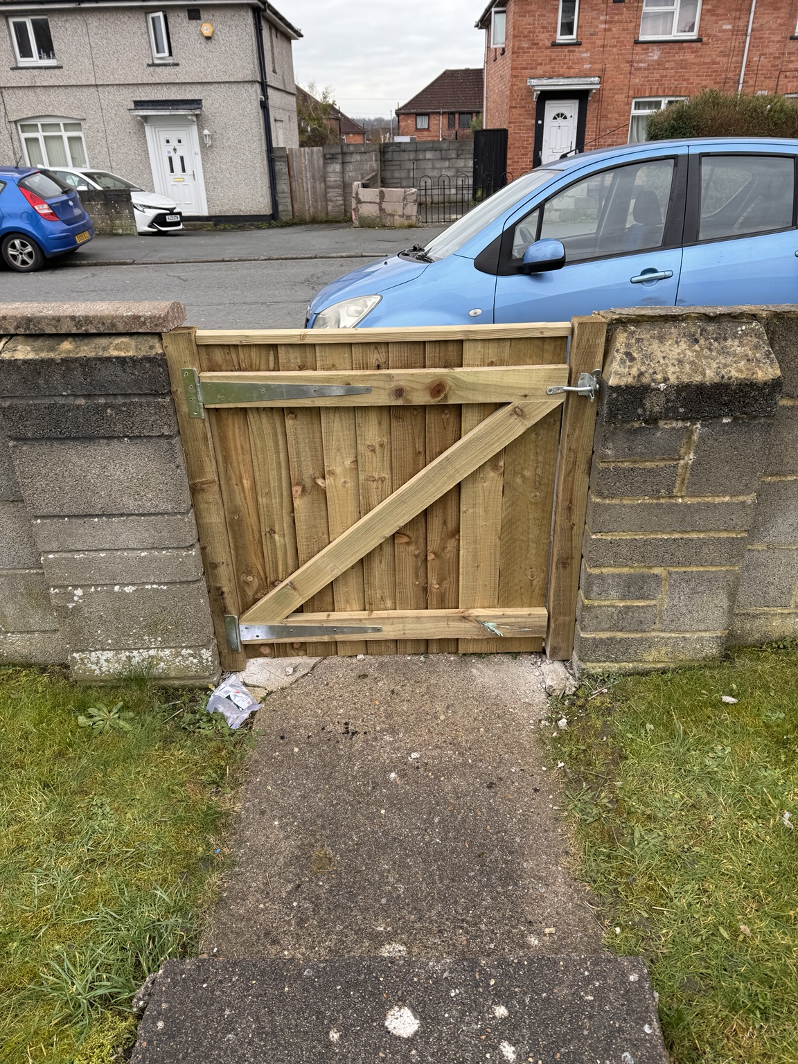 Single timber pedestrian gate between low walls